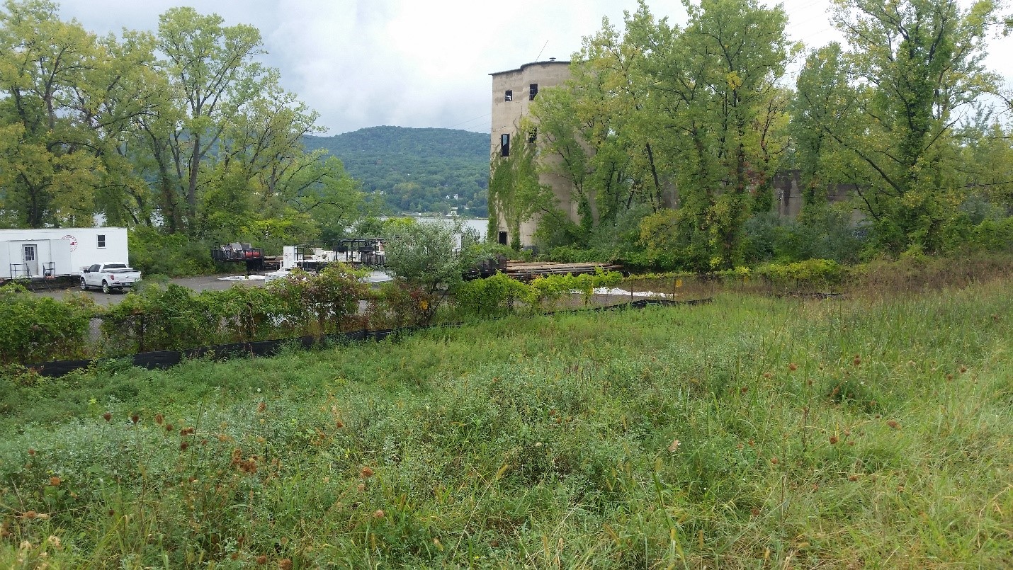 View looking west toward the Hudson River, the asphalt parking area, and former quarry structures from the existing access drive